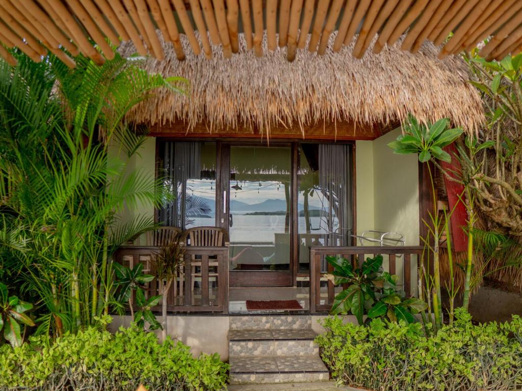 a house with a thatch roof and a patio at Krisna Bungalows and Restaurant in Sekotong