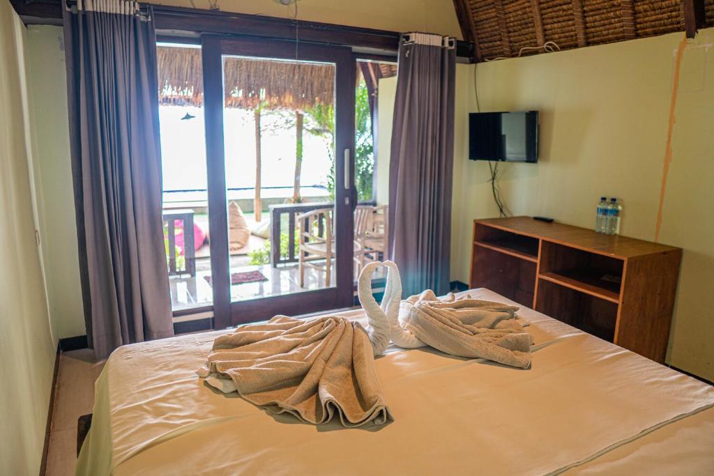 a bed with a towel on it in front of a window at Krisna Bungalows and Restaurant in Sekotong