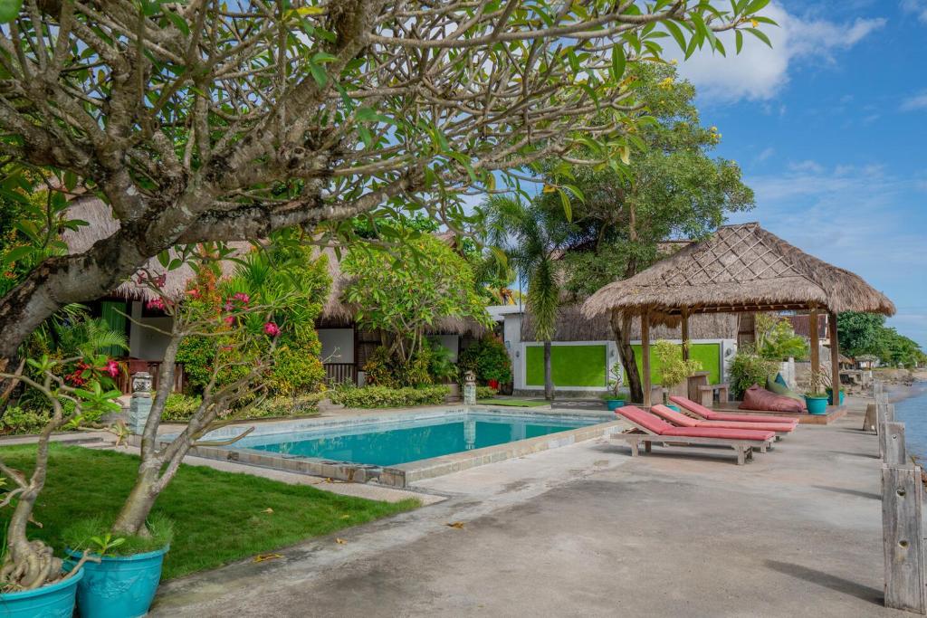 a resort pool with lounge chairs and a gazebo at Krisna Bungalows and Restaurant in Sekotong