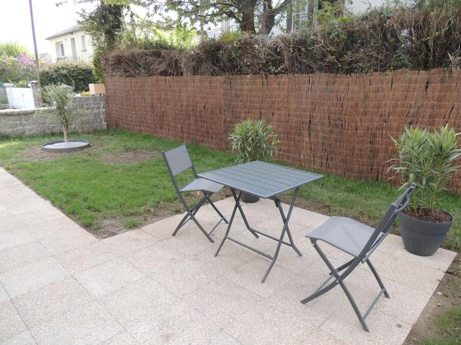 een picknicktafel en twee stoelen in de achtertuin bij Appartement entre terre et baie in Pontorson