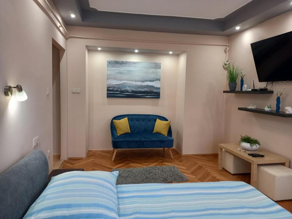 1 dormitorio con 1 cama azul y 1 silla azul en Zenit Apartman, en Makó
