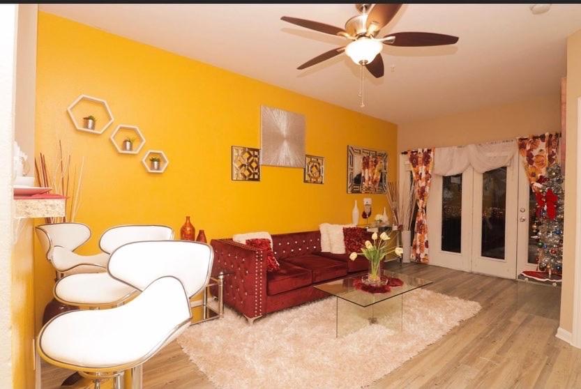 a living room with a red couch and white chairs at 5 star luxury 1 bedroom condo in Orlando