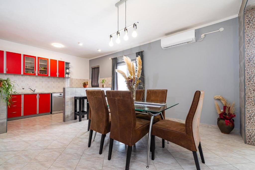 eine Küche und ein Esszimmer mit roten Schränken und einem Glastisch in der Unterkunft Apartment Thalia in Zadar