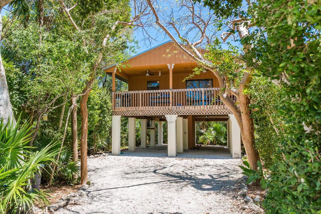 a house with a balcony in the middle of trees at The Florida Keys Treehouse in Marathon, FL in Marathon