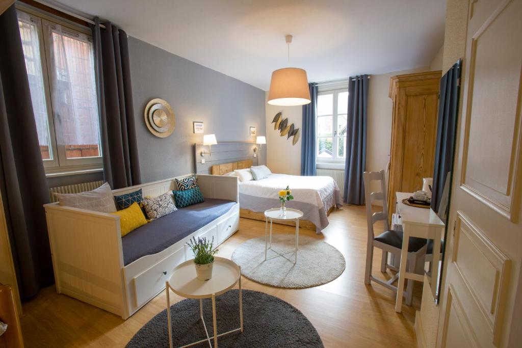 um quarto com uma cama, um sofá e uma mesa em Chambres Chez Laurence em Kaysersberg