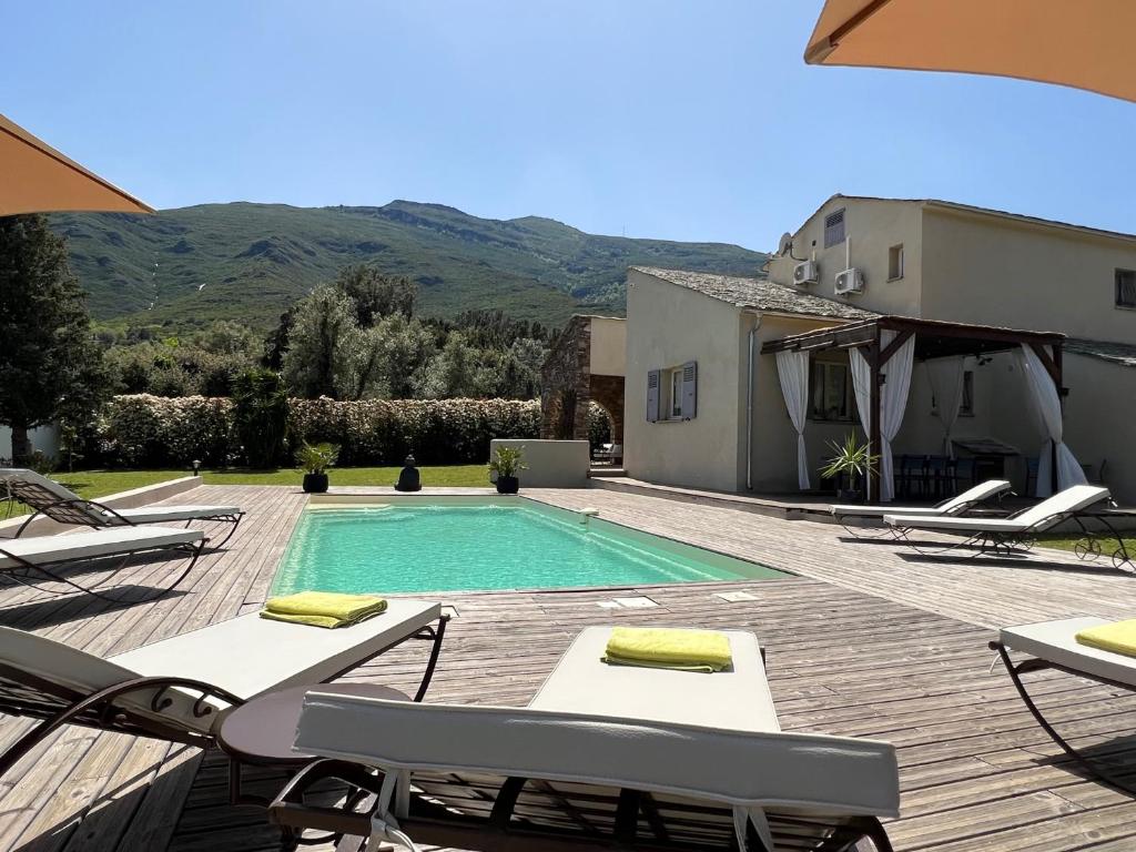 a swimming pool with lounge chairs and a house at Les 5 Arches in Sisco