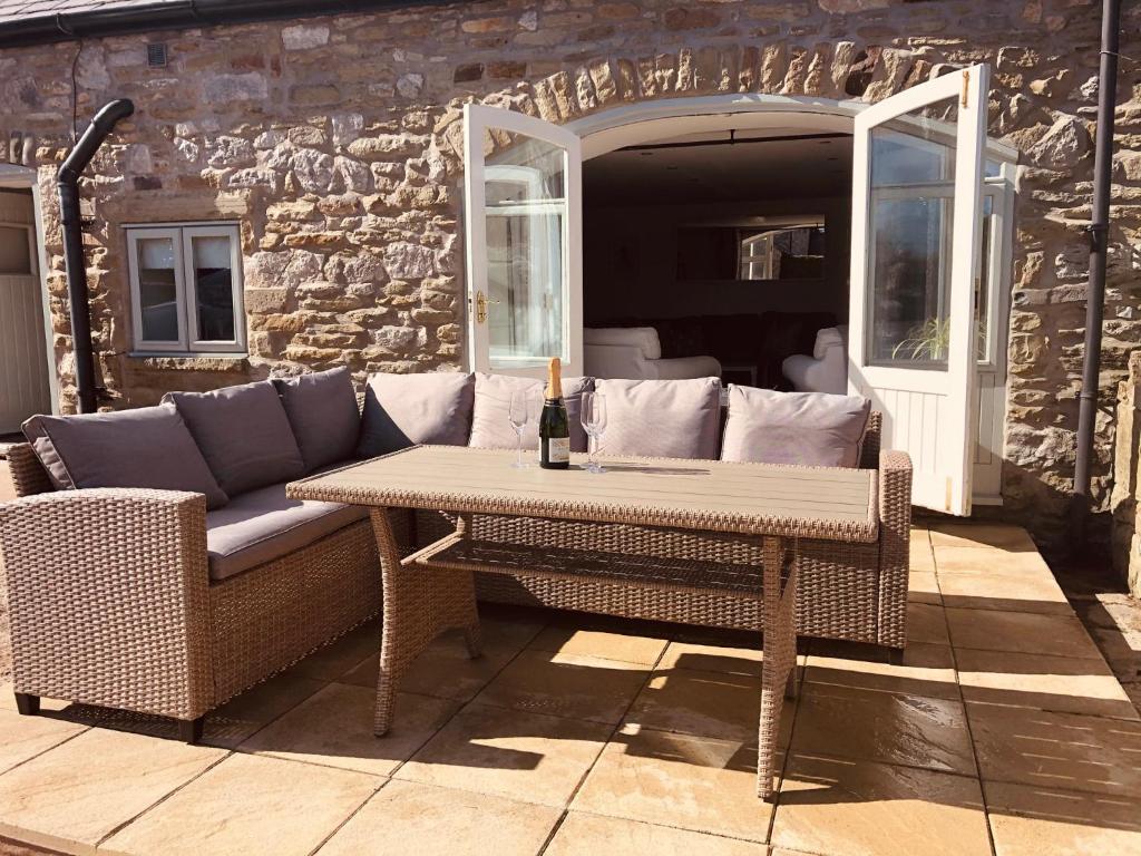 a table and chairs on a patio with a couch at Limekiln Cottage in Llanasa