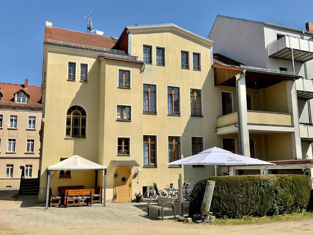 a large building with tables and umbrellas in front of it at Hotel Meridian in Görlitz