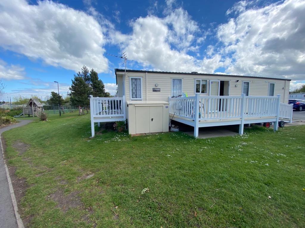 Seton Sands Haven Holiday Park - Platinum Caravan في Prestonpans: منزل أبيض صغير مع شرفة وساحة