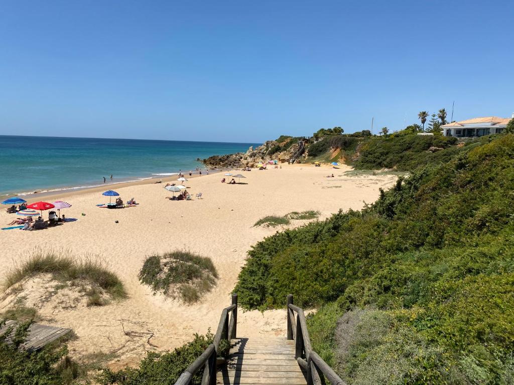 una escalera que conduce a una playa con gente en ella en Apartamento Retama Golf I, en Chiclana de la Frontera