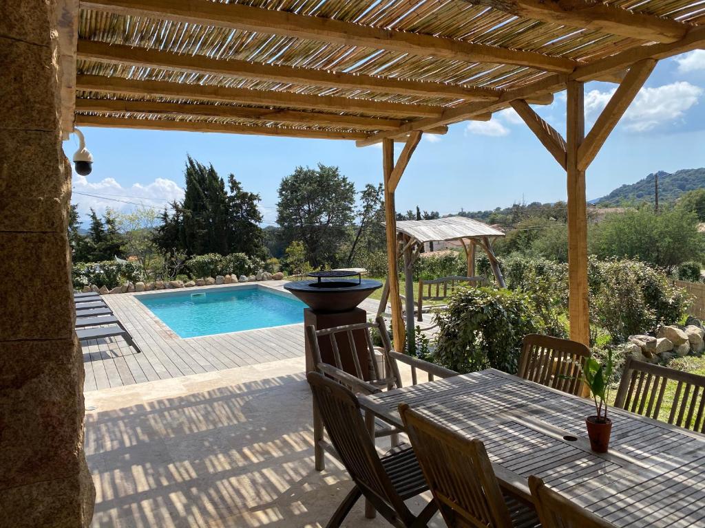 un patio con tavolo, sedie e piscina di Villa de charme avec piscine à Ajaccio ad Alata