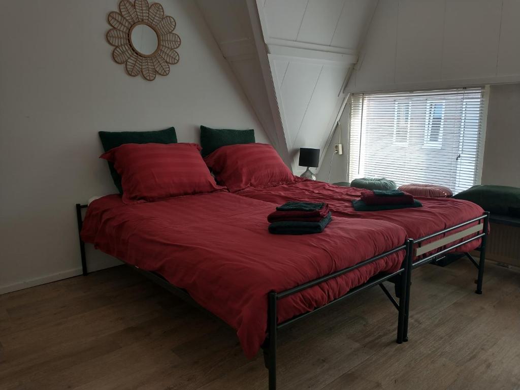 una camera da letto con un grande letto rosso con cuscini rossi di Voorstraat-Straatzicht Boven a Dordrecht