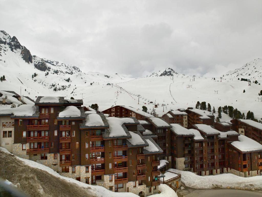 a building covered in snow with a mountain in the background at Résidence Pierre &amp; Vacances Emeraude in Belle Plagne
