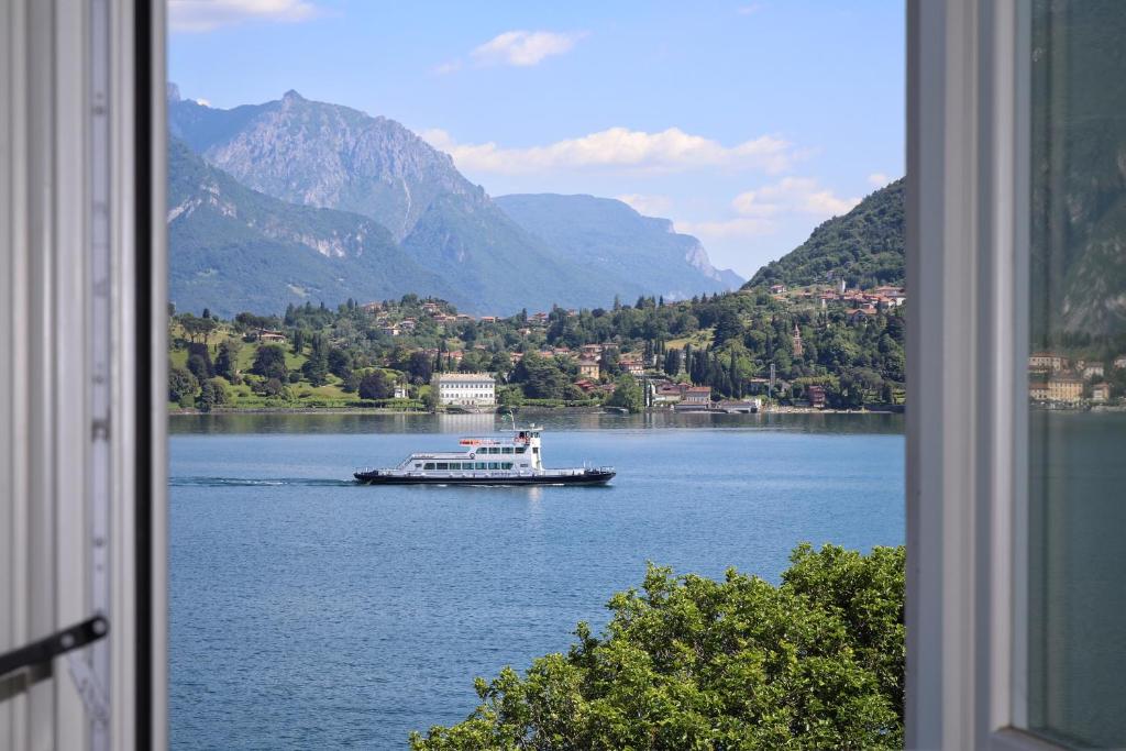 a boat on a lake with mountains in the background at Royal Cadenabbia in Griante Cadenabbia