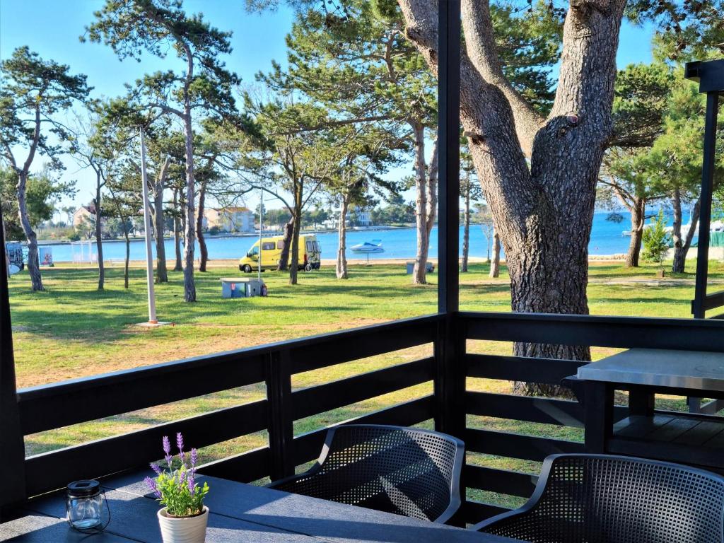 a table and chairs on a porch with a view of the water at Sand & Relax Privlaka - Mobile home "Lavanda" in Privlaka
