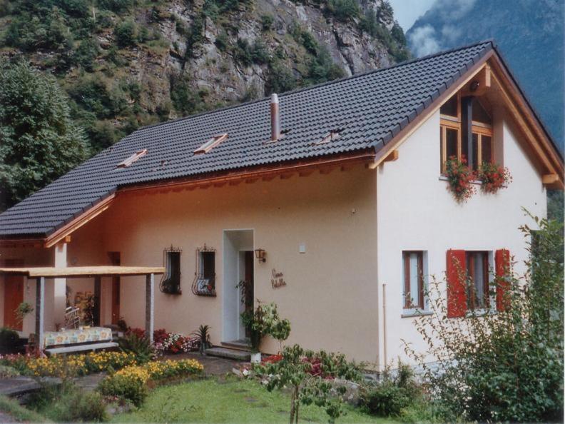 a small white house with a mountain in the background at Casa Betulla in Sonogno