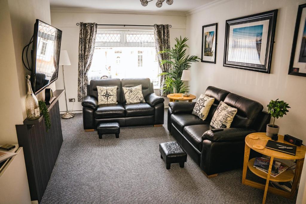 a living room with two leather couches and a television at Aunt Mary's in Belfast