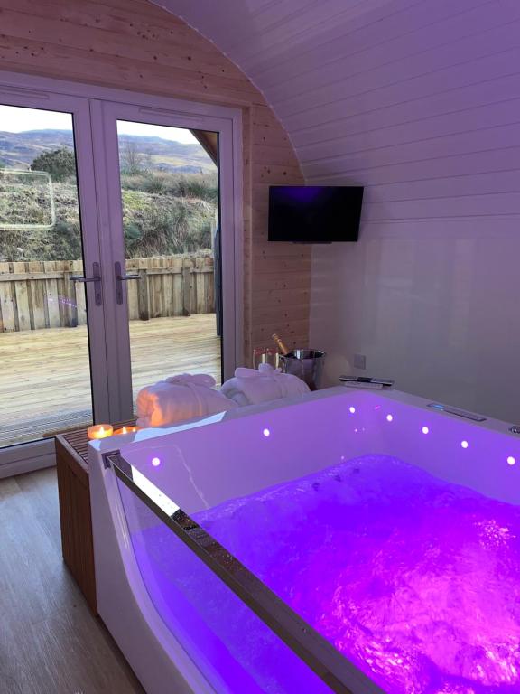a large purple tub in a room with a window at Apex Studio Pod & Jacuzzi Bath in Fort William