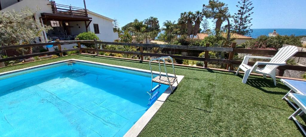 a swimming pool with two chairs next to a house at A Due Passi Dal Mare Con Piscina in Fontane Bianche