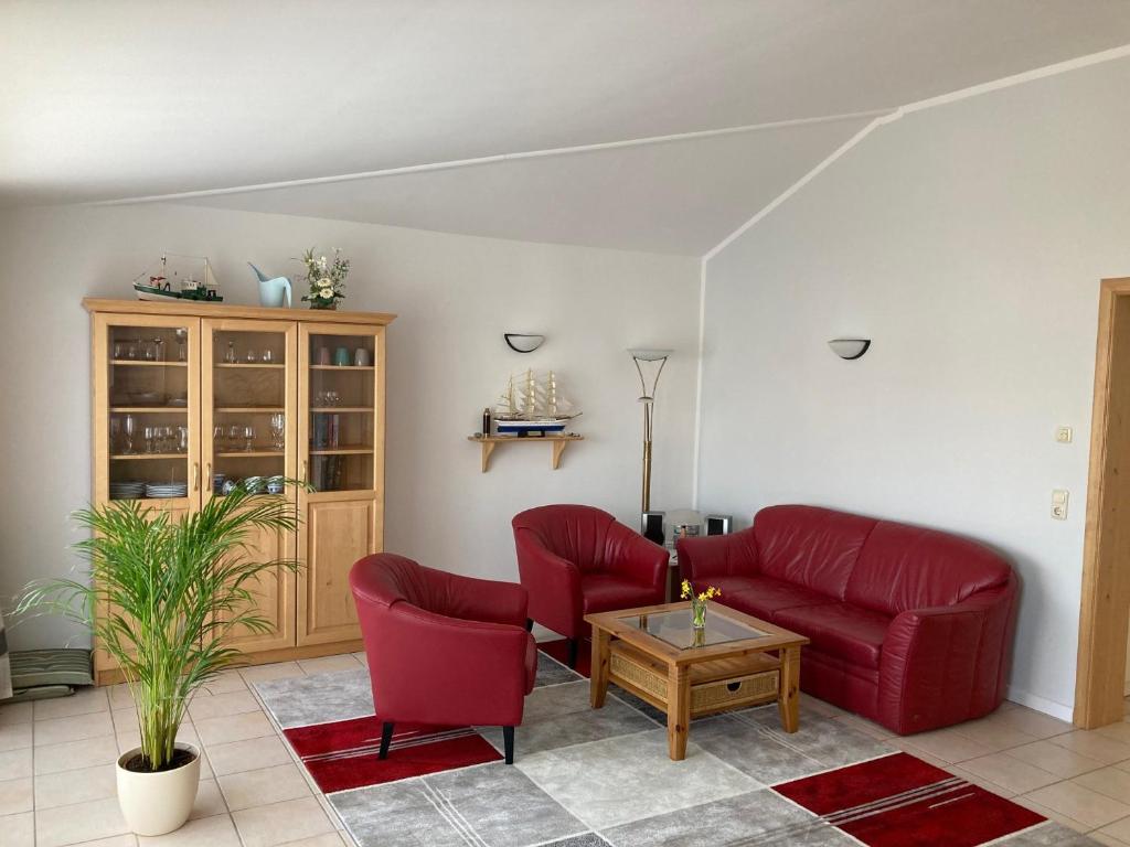 a living room with red chairs and a coffee table at Ferienwohnung Andresen Dünenstraße 16 in Rerik