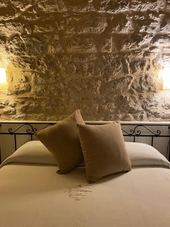 a bed with two pillows and a stone wall at Agriturismo Pettino in Campello sul Clitunno