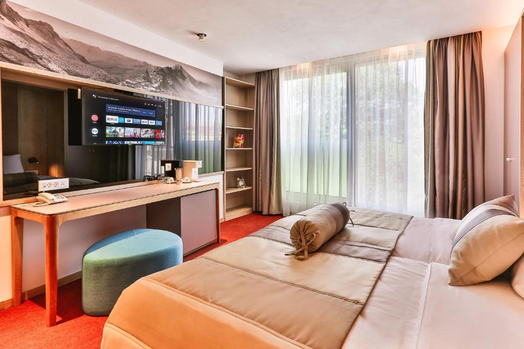 un ampio soggiorno con divano e scrivania di Carine Hotel Centar a Podgorica