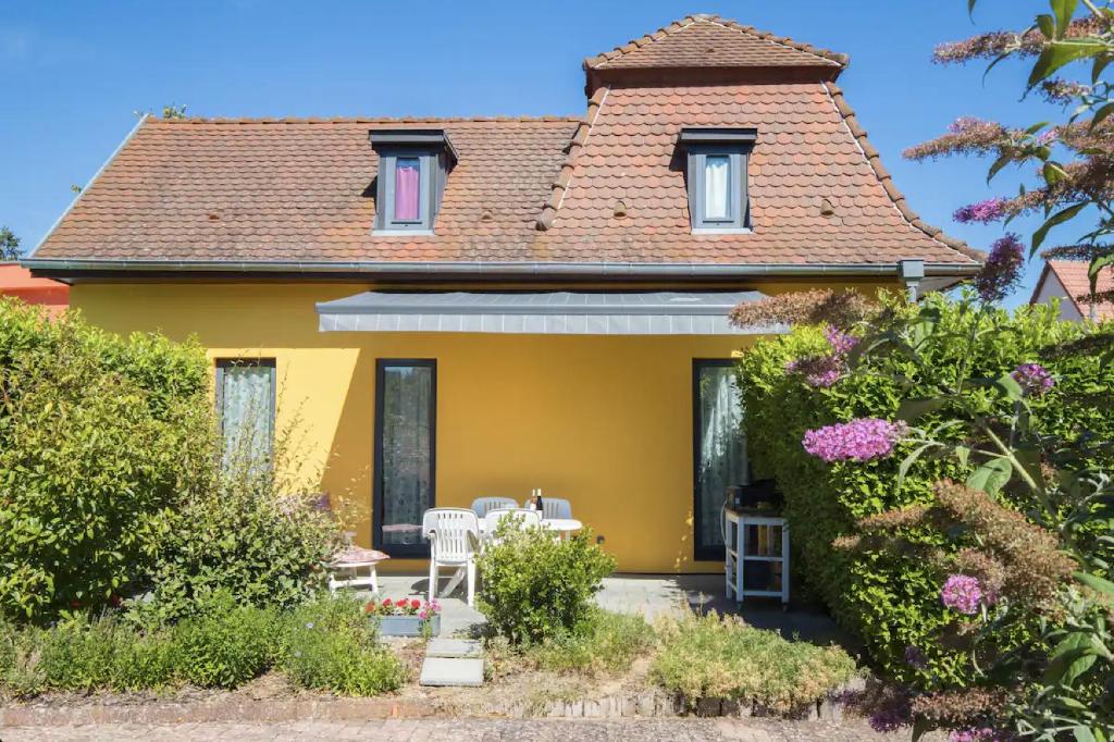 ein gelbes Haus mit einem Tisch und Stühlen in der Unterkunft Les Bains de Rosheim in Rosheim