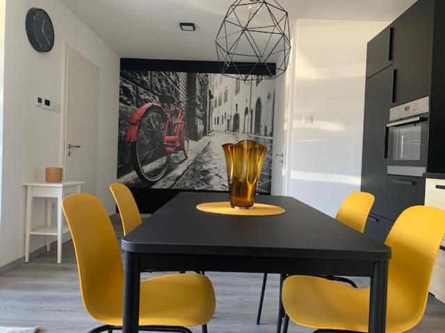 a dining room with a black table and yellow chairs at New Home Guest House in Gödöllő