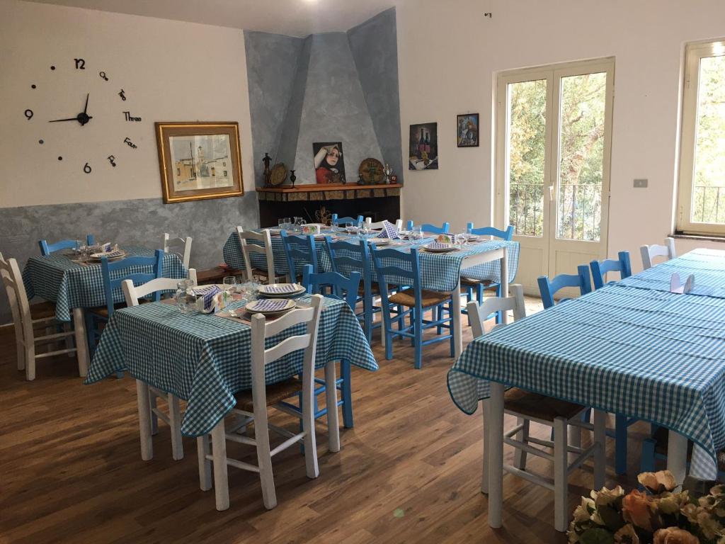 comedor con mesas y sillas azules y reloj en AZIENDA AGRITURISTICA S'ARGALASI - B&B - AFFITTACAMERE Loc S'Argalasi Austis en Austis