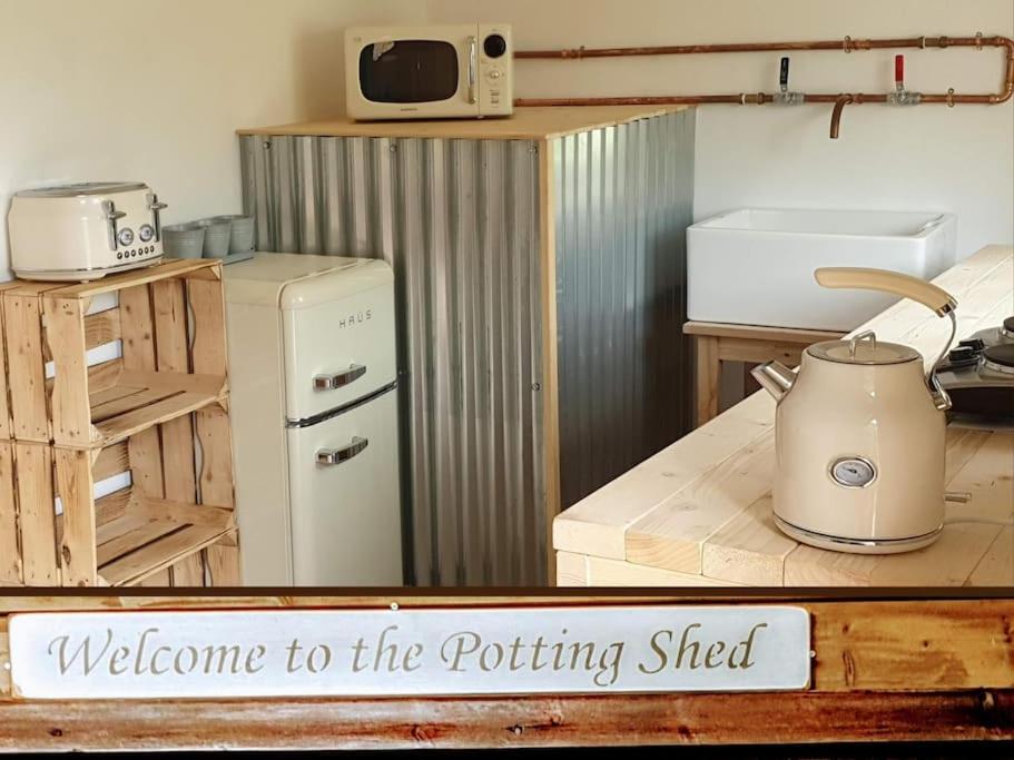 a kitchen with a stove and a refrigerator at The Potting Shed near Tenby, 100" Projector, Four poster bed, On-site HOT TUB access via Spa Pack in Tenby