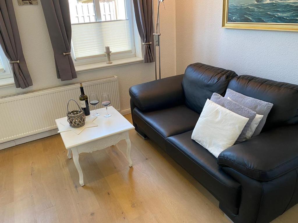 sala de estar con sofá de cuero negro y mesa en Ferienwohnung „Ole Karkenwech“ Husum-Rödemis, en Husum