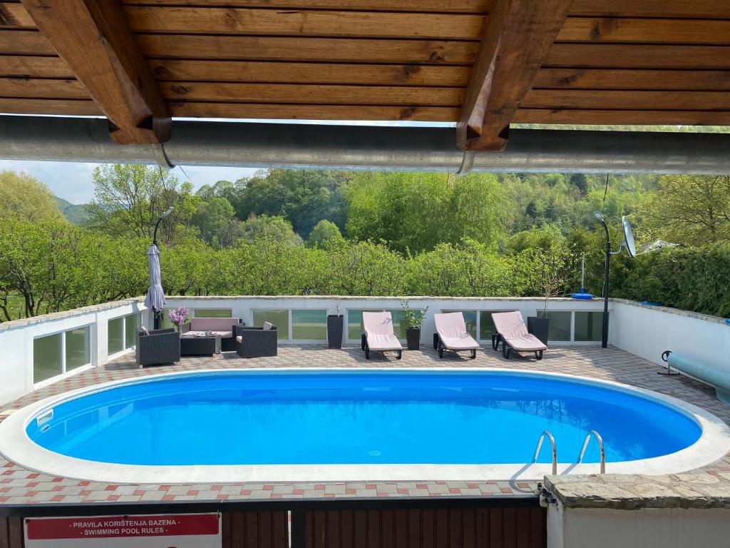 a large swimming pool with chairs and a roof at Villa Enio in Bihać