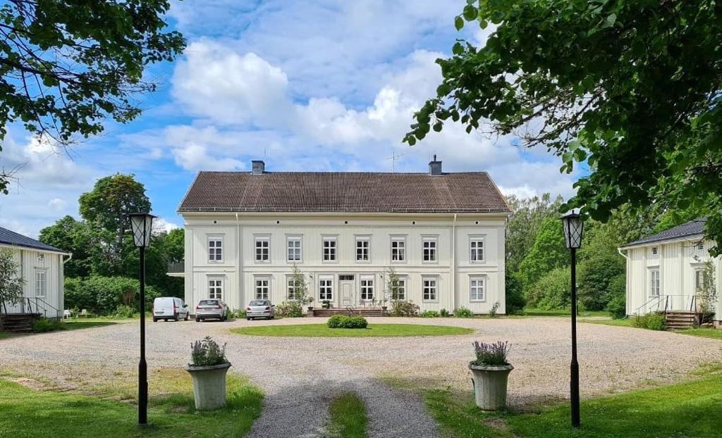 uma grande casa branca com carros estacionados na entrada em Risberg Herrgård em Hagfors