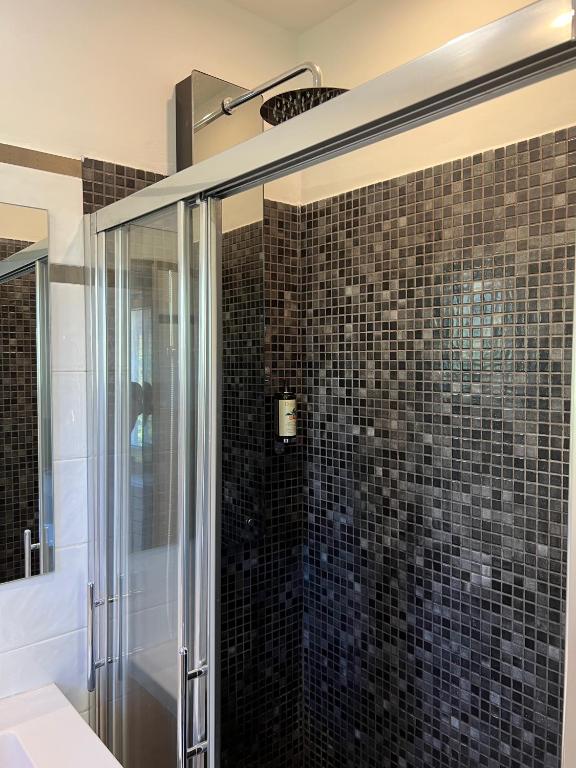 a bathroom with a shower with black tiles at Appartements Saint Pancrace in Corte