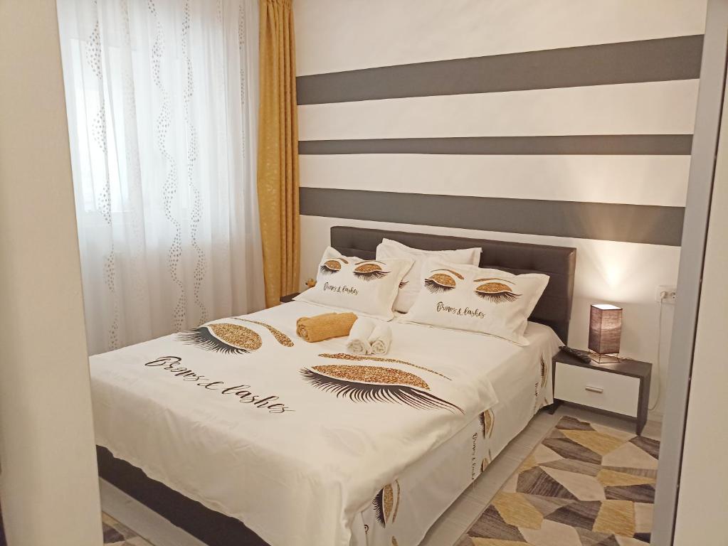 1 dormitorio con cama blanca y pared a rayas en Apartament Sofy2, en Băile Herculane