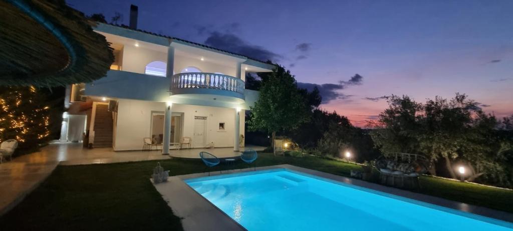 eine Villa mit einem Pool vor einem Haus in der Unterkunft HEAVENLY VIEWS-2-APARTMENT with POOL VIEW CLOSE TO THE BEACH! in Oropos