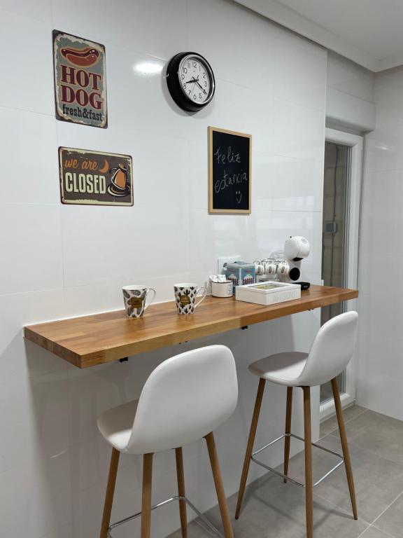 a kitchen with a wooden counter and two white chairs at Apartamento Cuatro Estaciones in Calahorra