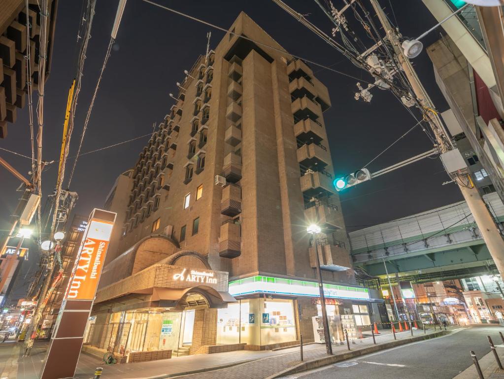 un edificio alto en una calle de la ciudad por la noche en Shinsaibashi ARTY Inn en Osaka