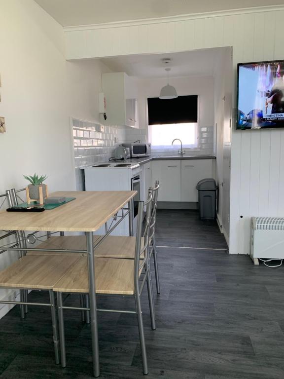 a kitchen with a table and chairs and a television at Bulldog holidays 243 in Hemsby