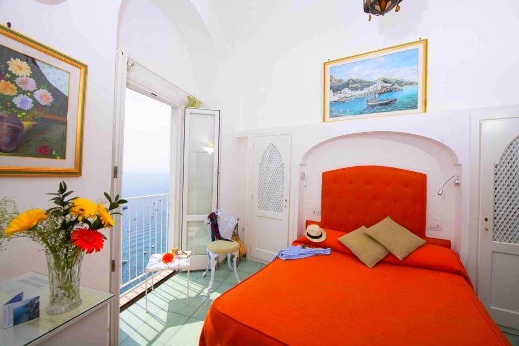 1 dormitorio con cama roja y balcón en Hotel La Ninfa, en Amalfi