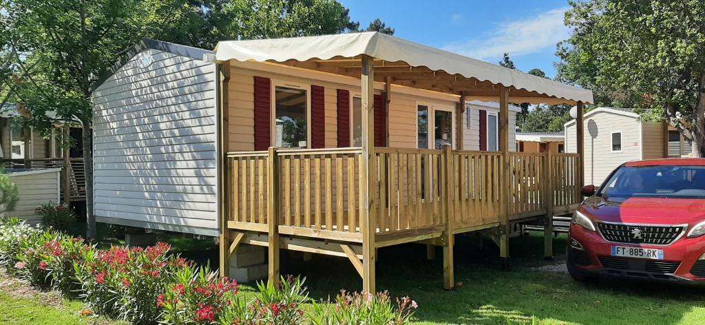 a large wooden house with a canopy on a yard at Mobil Home Camping Les VIVIERS, Claouey in Claouey