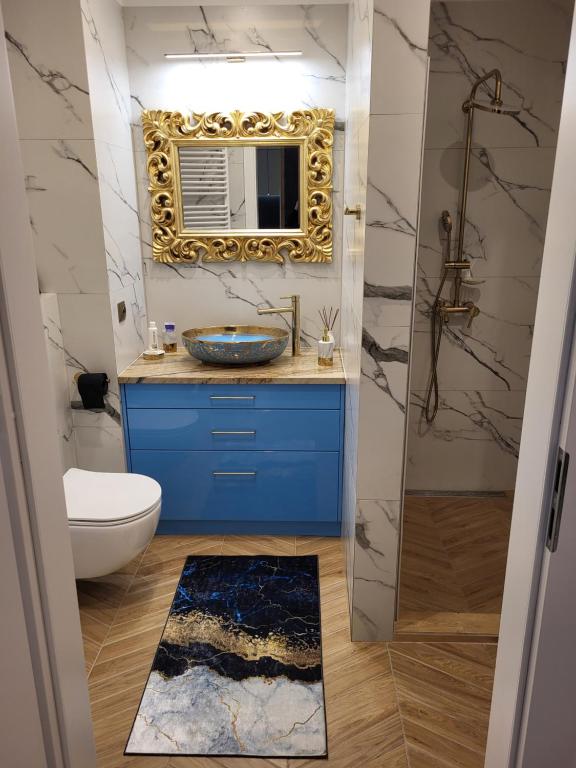 La salle de bains est pourvue d'un lavabo bleu et d'un miroir. dans l'établissement Apartament SixtySix 66 z kominkiem, à Białystok