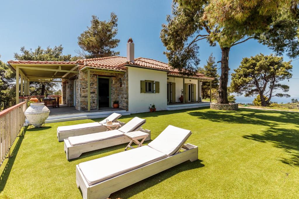 a backyard with lounge chairs and a house at Aegean View Villa in Skopelos Town