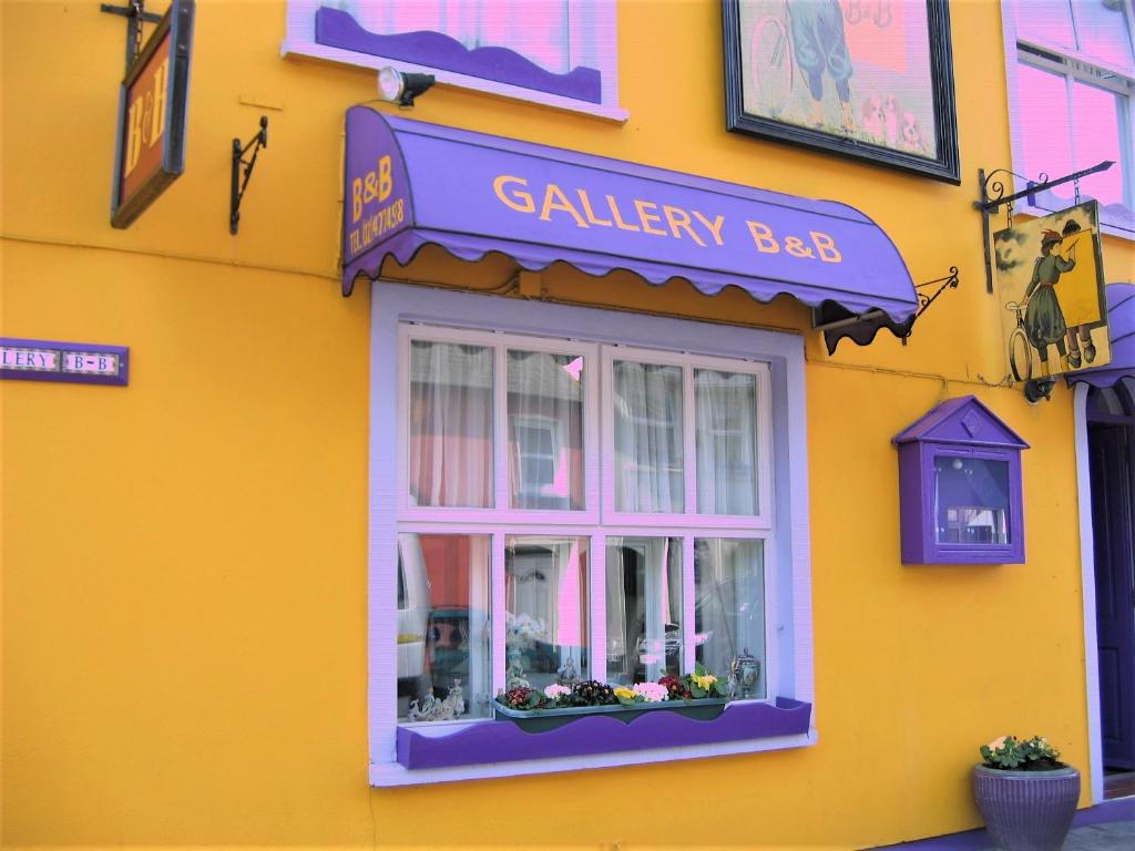 een geel gebouw met een raam en een bord erop bij The Gallery B&B, the Glen, Kinsale ,County Cork in Kinsale