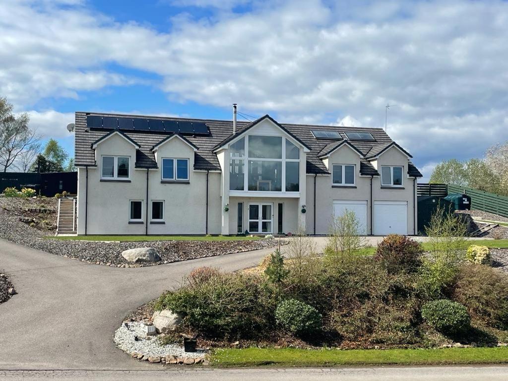 a large white house with blue windows and a driveway at Strath View on the NC 500 in Culbokie