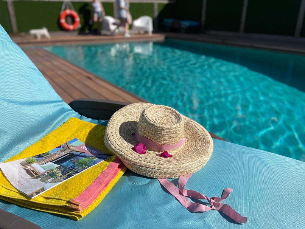ein Strohhut und ein Buch auf einem Tisch neben einem Pool in der Unterkunft Julia’s Garden in Cuarte de Huerva