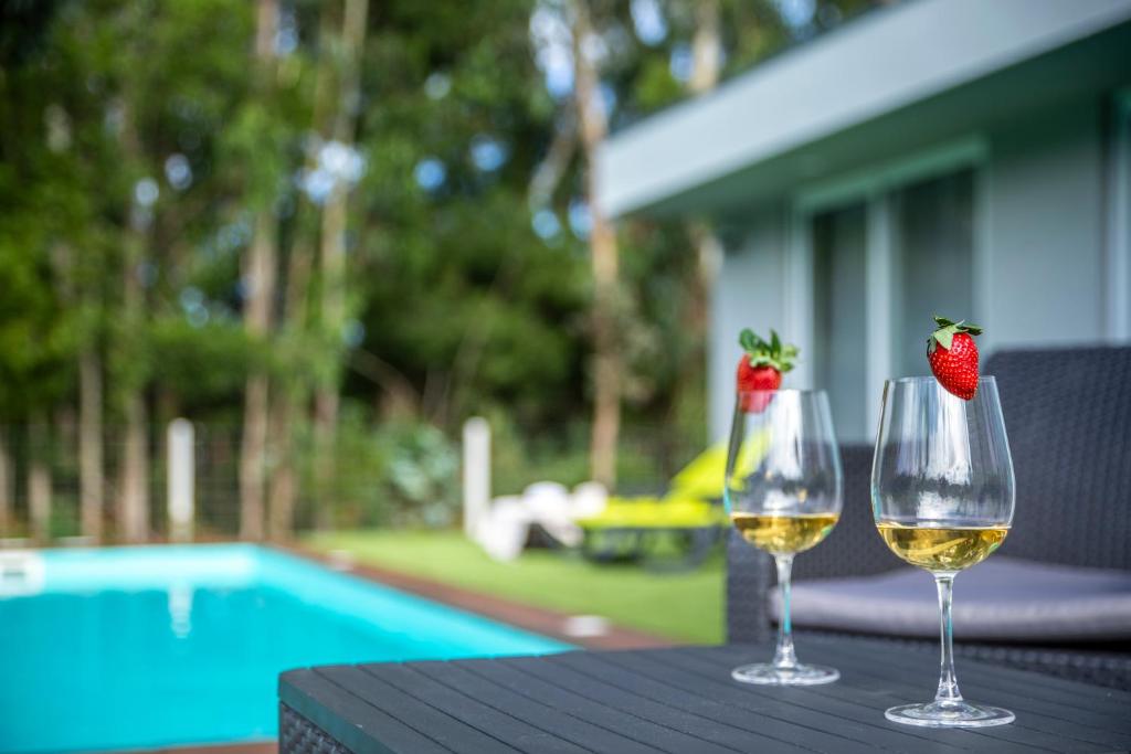 deux verres de vin blanc et de fraises sur une table dans l'établissement Villa Rencanto – um espaço com a sua assinatura, à Caminha