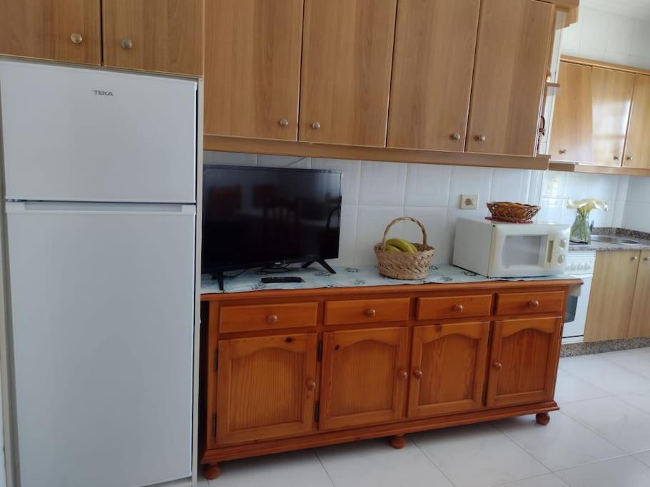 cocina con nevera blanca y microondas en Apartamento en San Vicente de O Grove, en O Grove