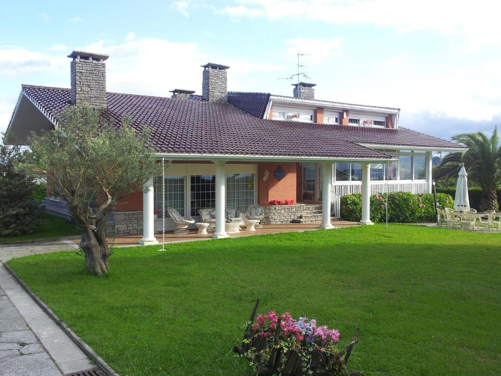 ein Haus mit einem grünen Garten mit Blumen davor in der Unterkunft El Tejado de Santa Ana in Barrika