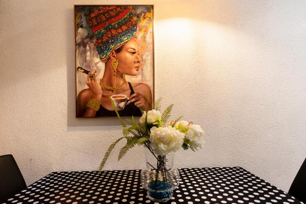 a vase of flowers on a table with a painting at Little House in Center in Almería